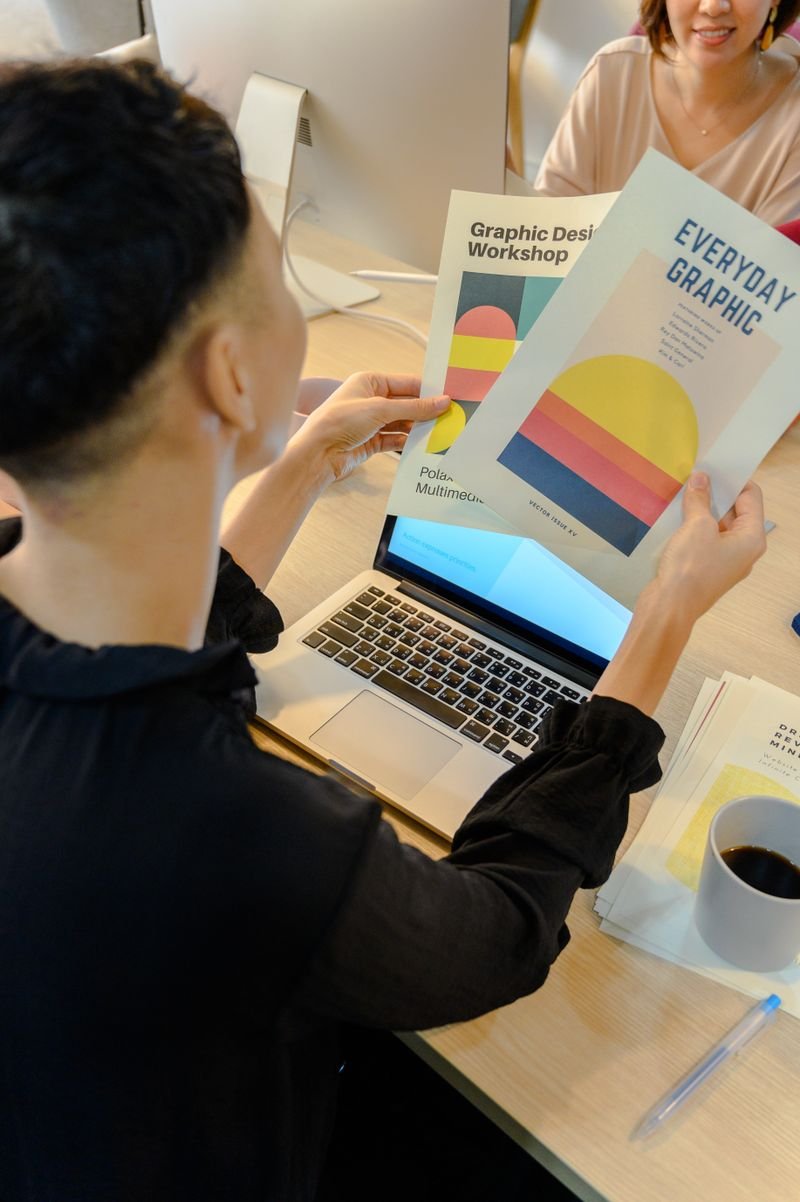 Designer reviewing colourful logo and brand identity concepts on paper and laptop — logo and branding design service