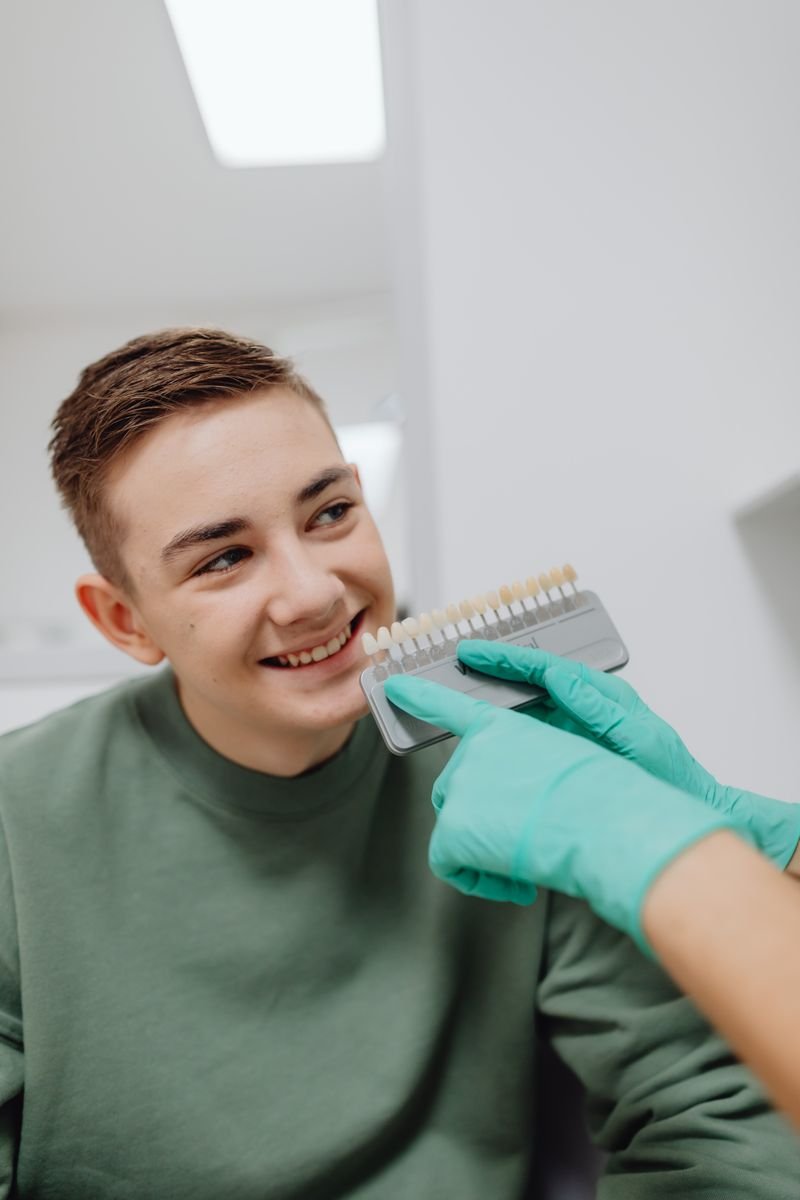 Dentist showing a smiling patient a tooth-shade guide — dental website design service for US clinics